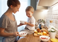 preparation of a family breakfast. mother and baby son cook porridge in morning