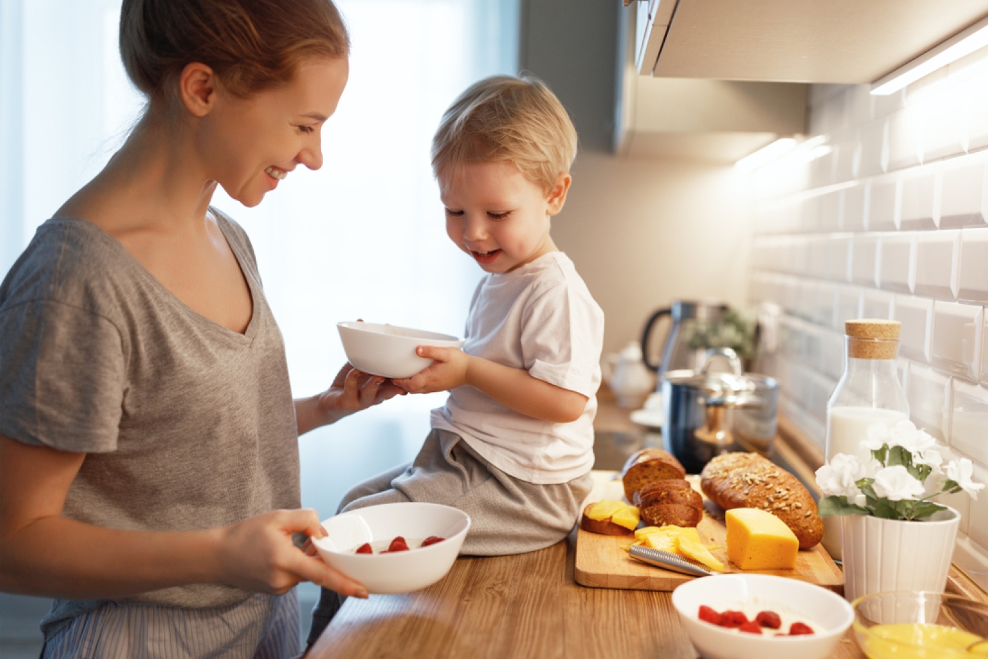 preparation of a family breakfast. mother and baby son cook porridge in morning