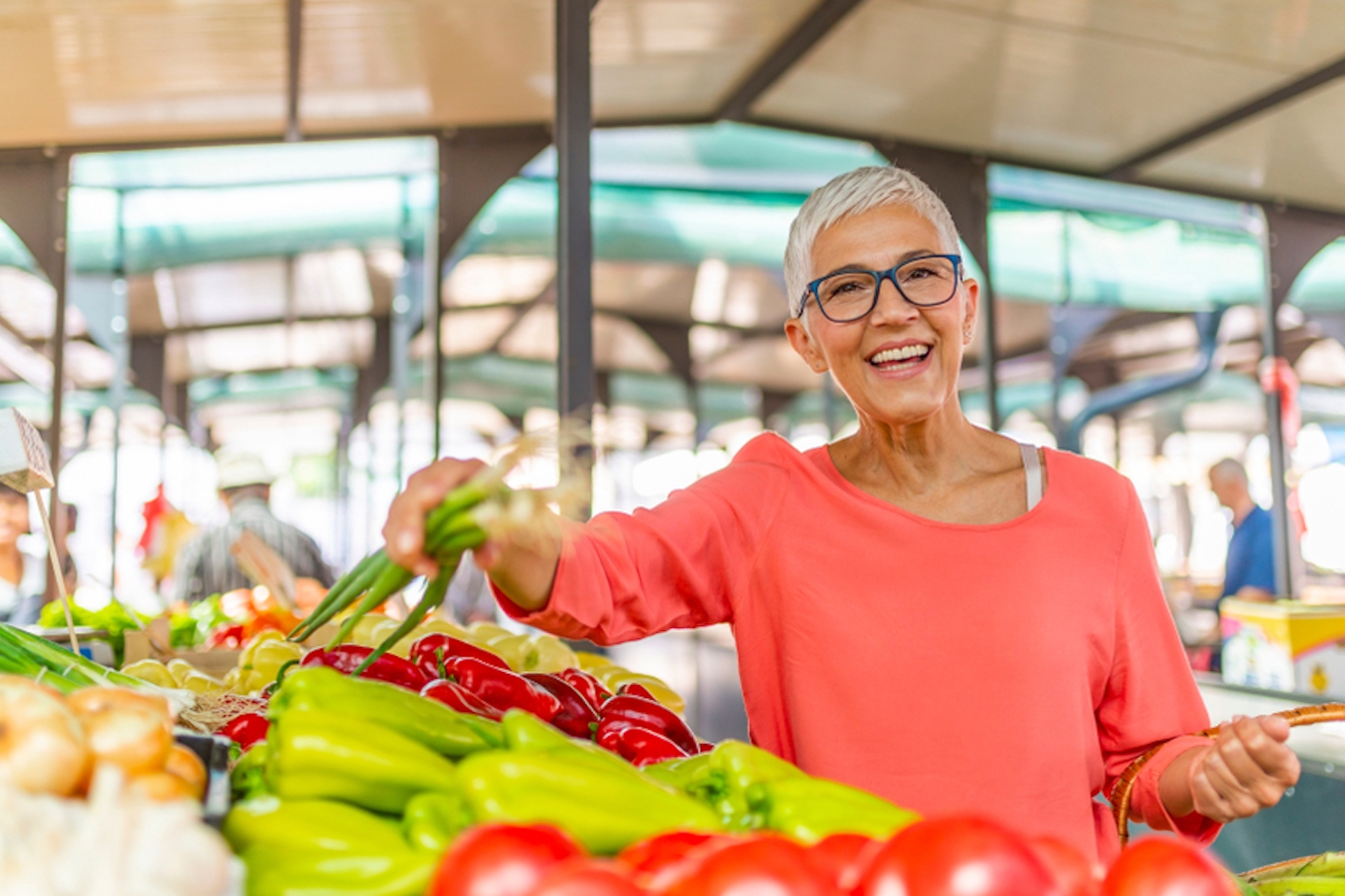 Beautiful senior woman buying vegetables at a farmers market. Woman on greenmarket. Senior woman picking fresh produce at the market. Farmers Market Shopping Mature Woman