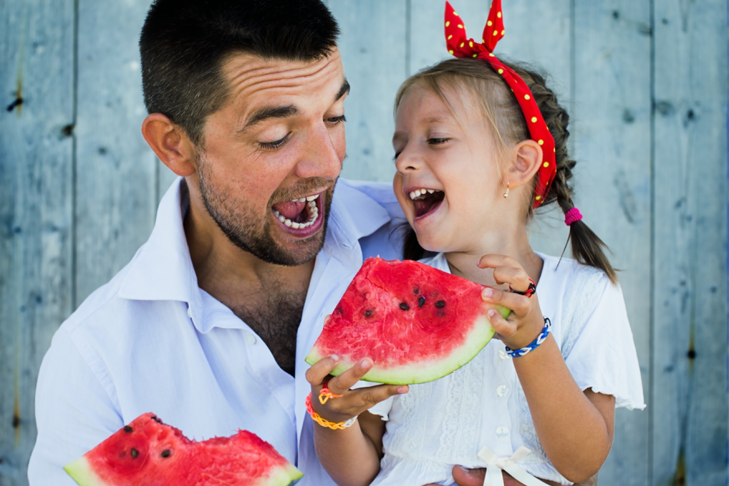 happy father playing with cute little daughter holding watermelon