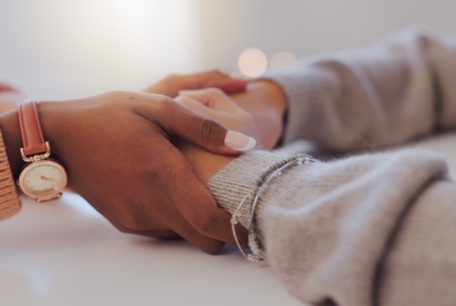 Home, holding hands and women with comfort, support and compassion in living room. Closeup, people and friends with grief, loss and sad with love, unity and trust with empathy, sympathy and help
