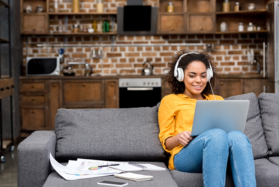 A woman uses a laptop while sitting on her couch